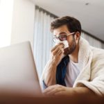 Young man working at home because of flu