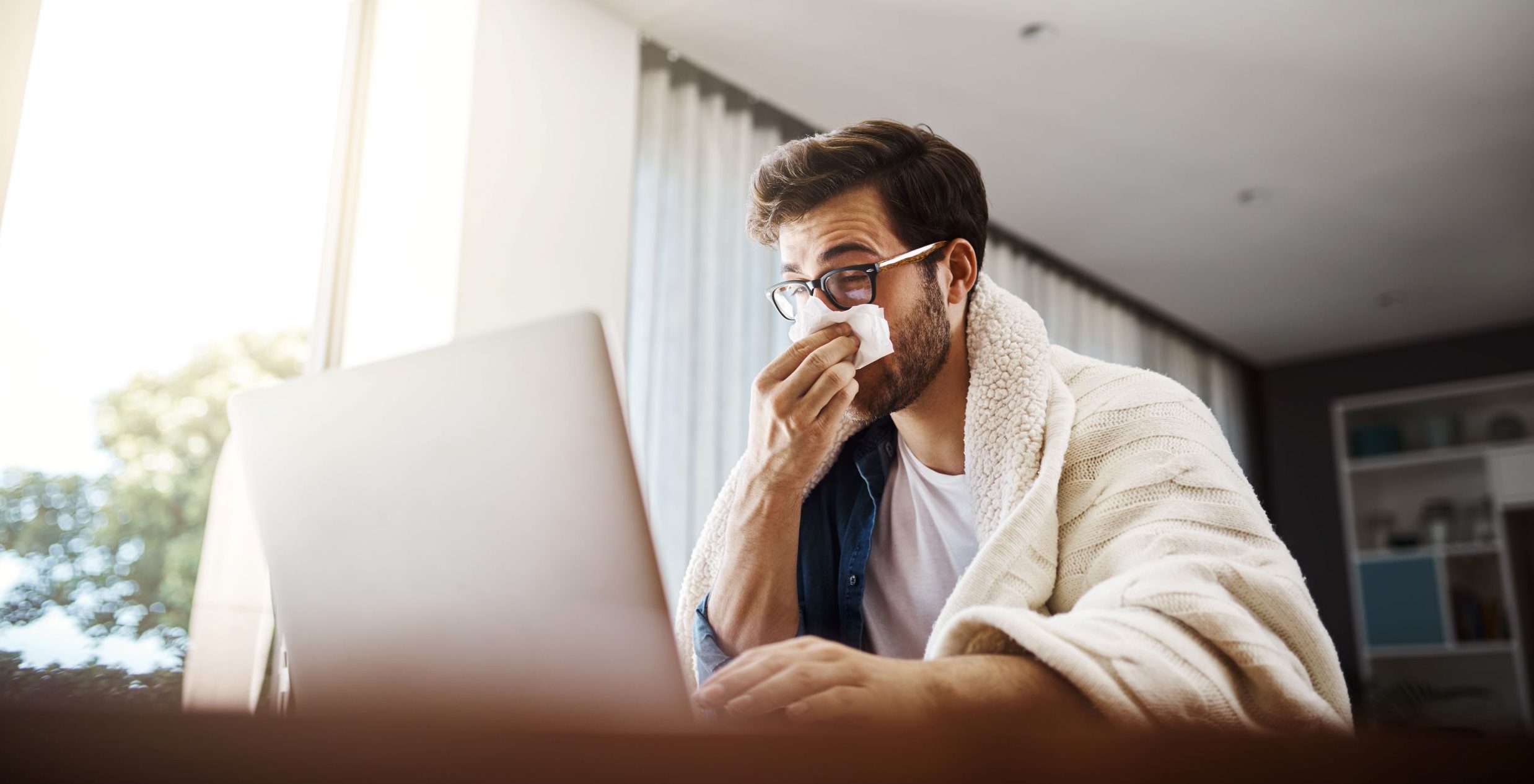 Young man working at home because of flu